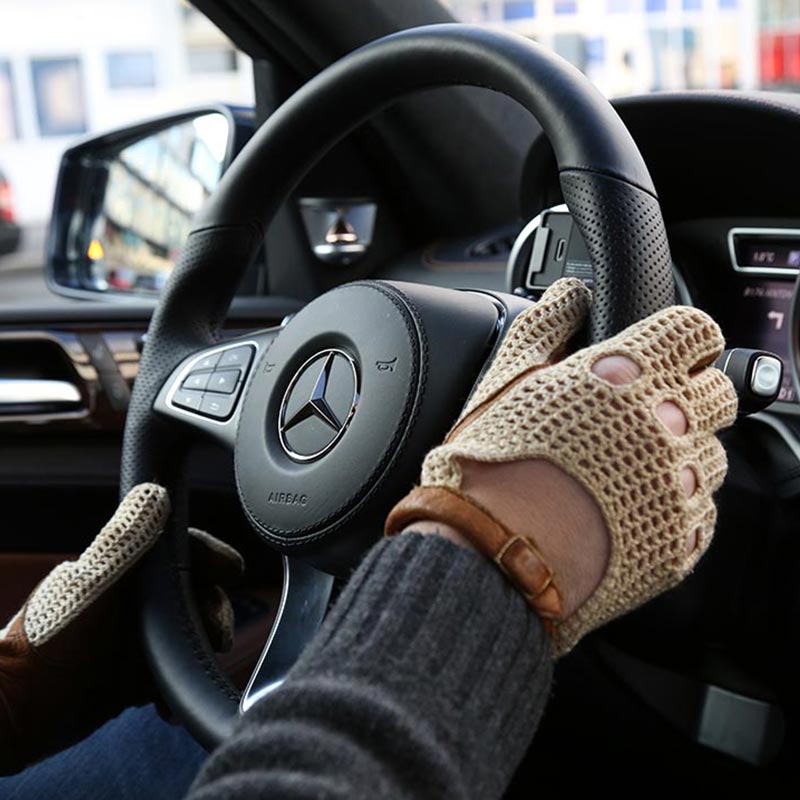Hands wearing driving gloves on a Mercedes steering wheel